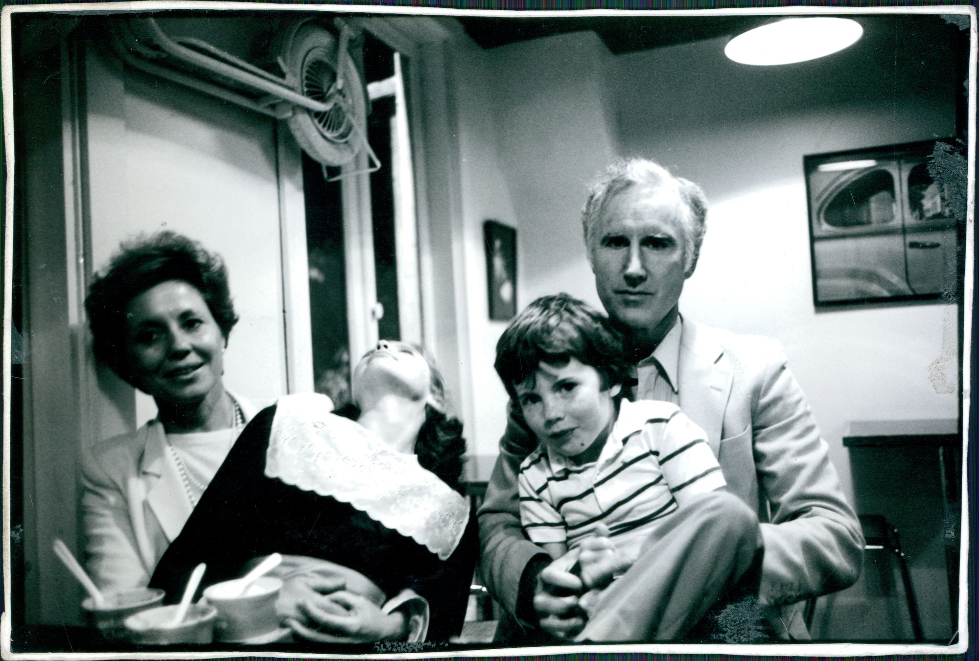 a black and white photo of our family - Anne and Phil sitting, each with a wiggling kid, ages around 11 and 9, in their laps.