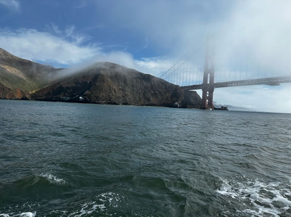 a view of the water and hills from the Bay towards the north tower of the golden gate, with broken fog. 